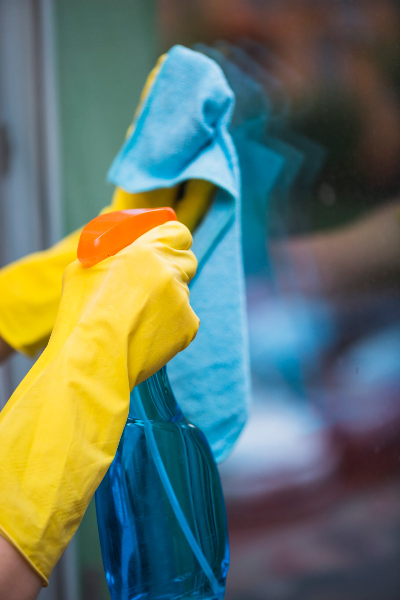 housekeeper spraying detergent with spray bottle glass window